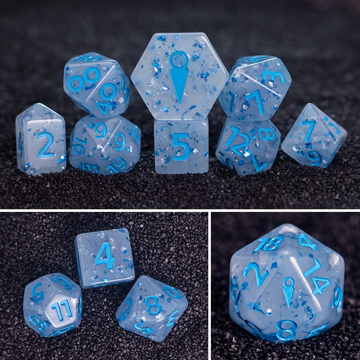 Widow's Wraith 8-piece resin RPG dice set on dark sand: milky blue with blue & silver foil